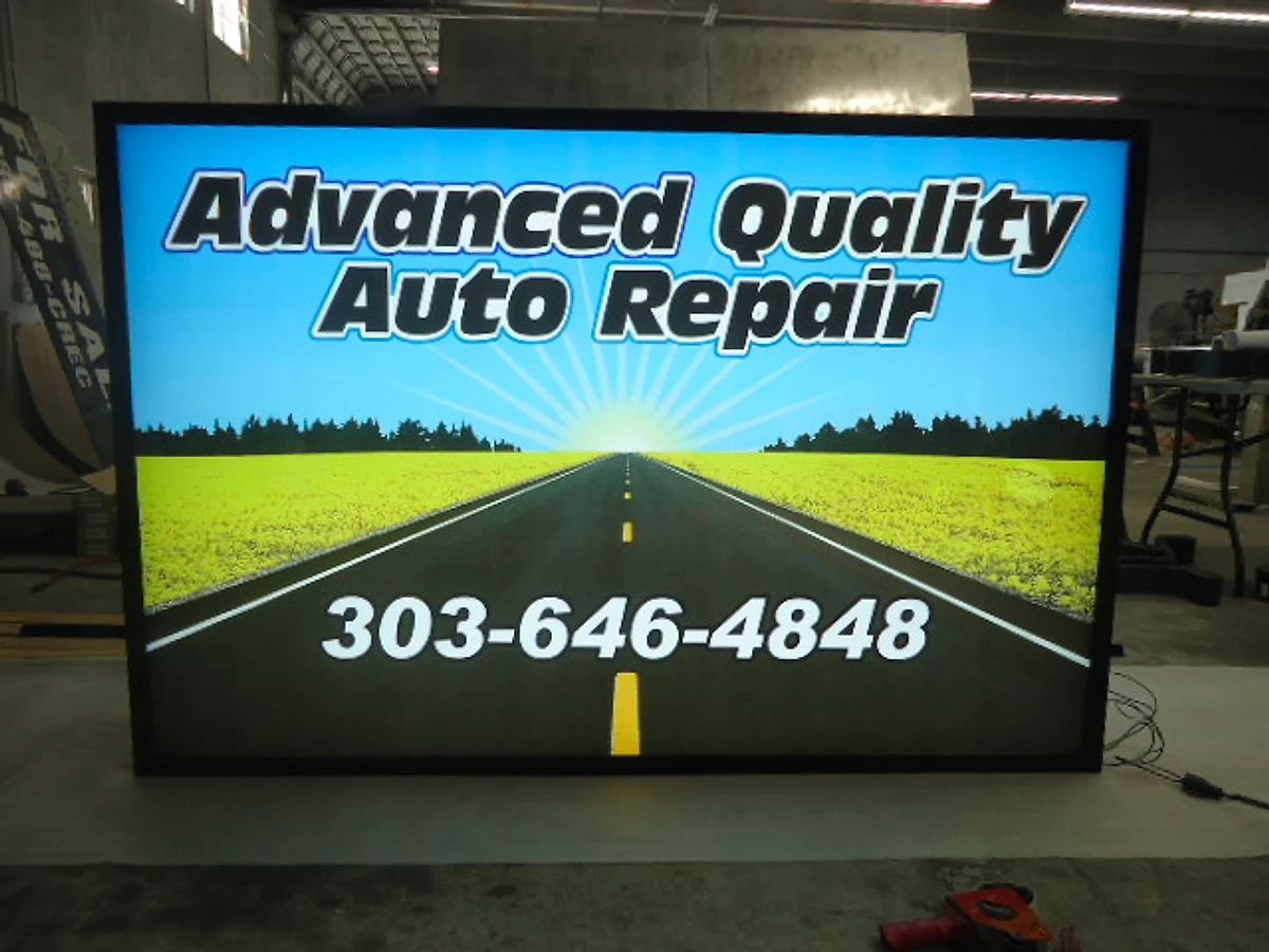 A full-colour illuminated cabinet sign for Advanced Quality Auto Repair, lit on the shop floor